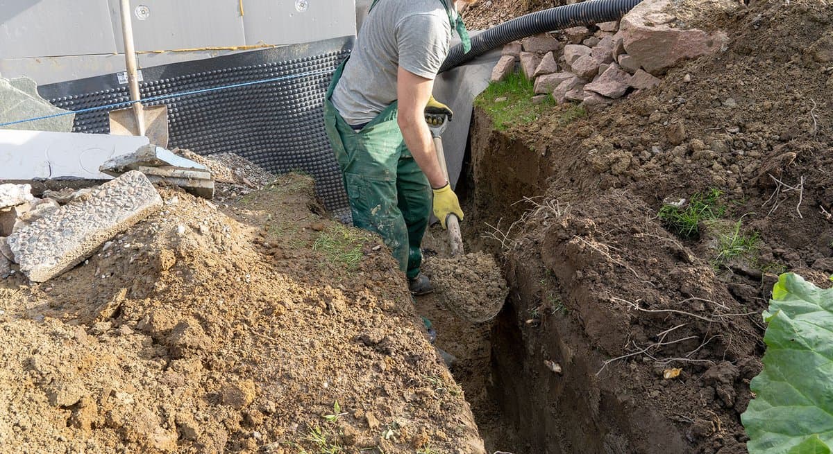 Gutter downspout connected to solid green PVC pipe going underground in a lawn